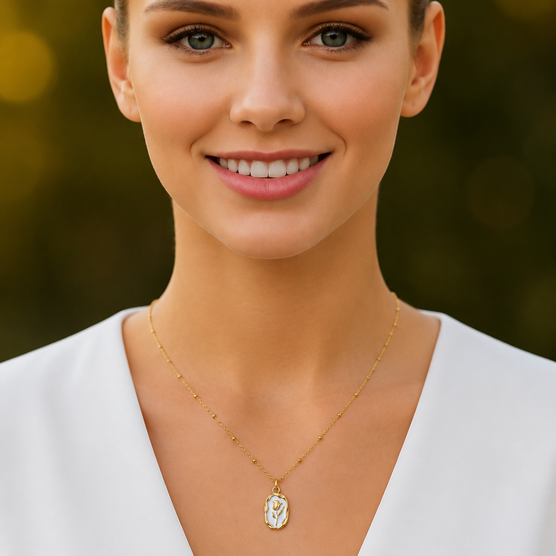 Woman wearing a gold tone necklace with a pendant against a blurred green background