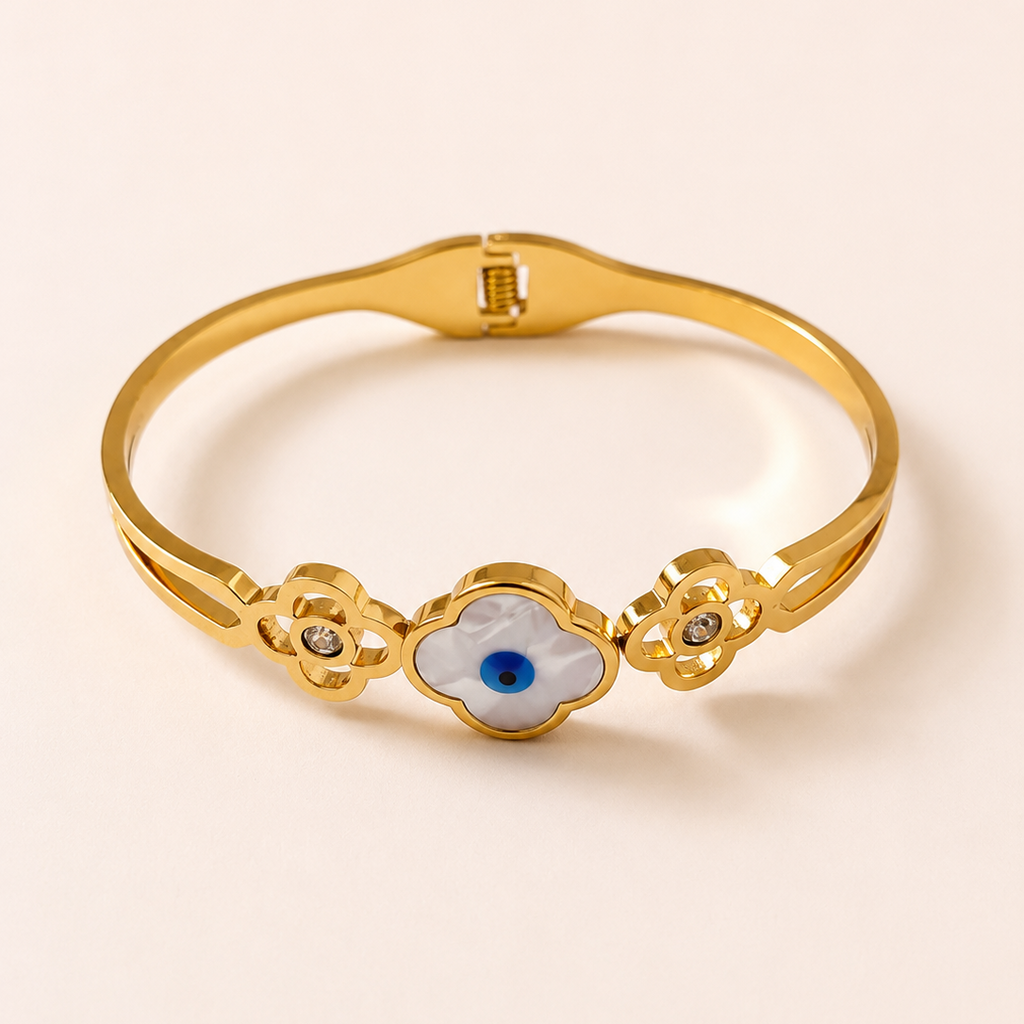 Gold tone bracelet with an eye design on a beige background