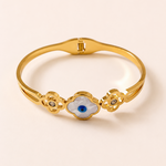 Gold tone bracelet with an eye design on a beige background