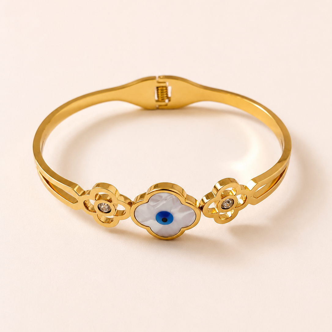 Gold tone bracelet with an eye design on a beige background