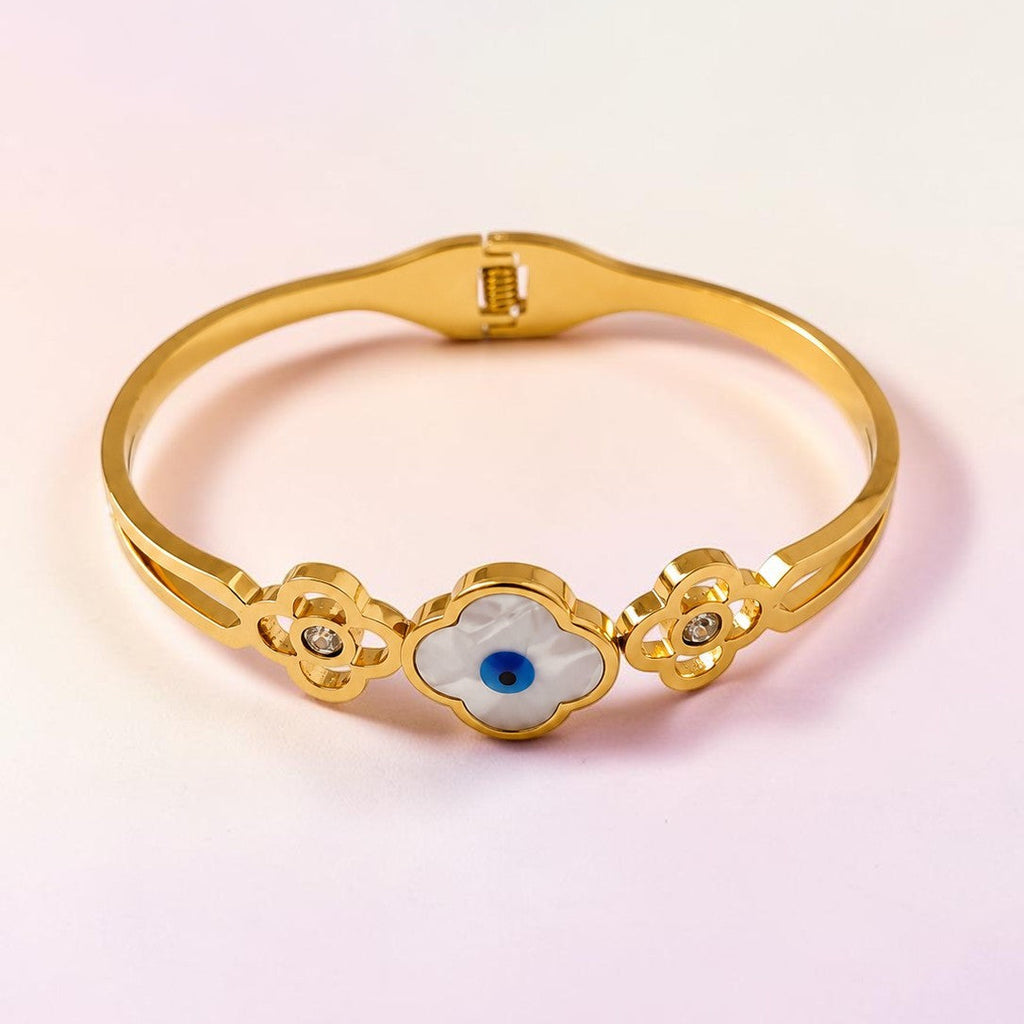 Golden bracelet with a central blue gemstone on a gradient pink background
