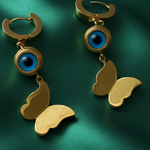 Gold tone earrings with blue eye design on a green background