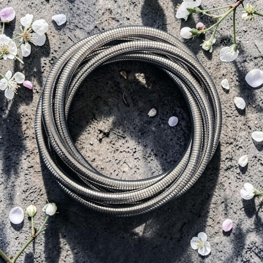 Coiled metal hose on a concrete surface with small flowers