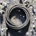 Coiled metal hose on a concrete surface with small flowers