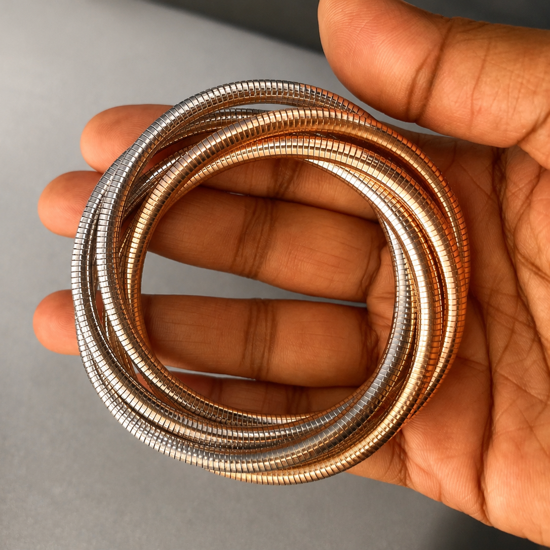 Hand holding a coiled metal tube against a neutral background