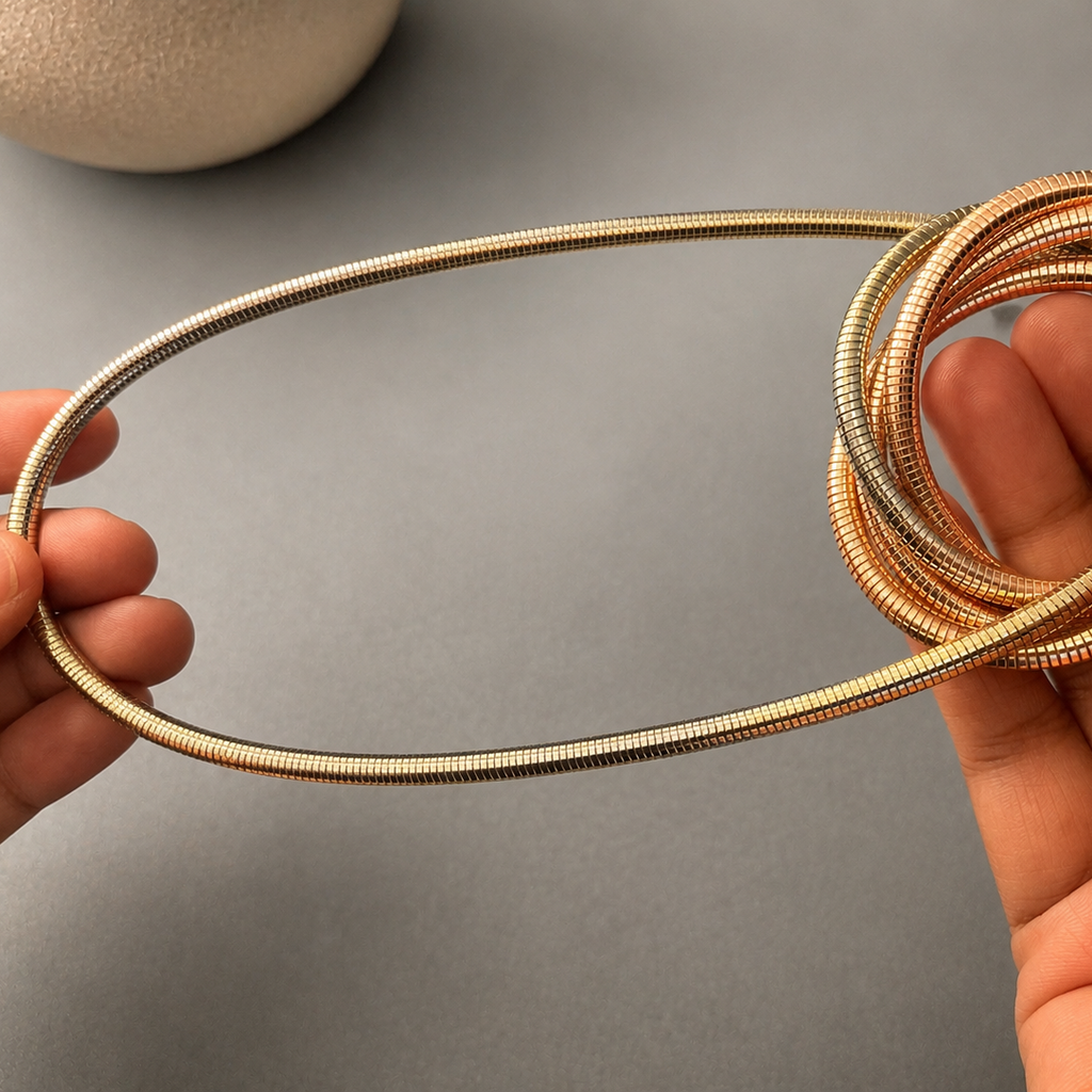 Coiled metal tube held between two hands against a gray background