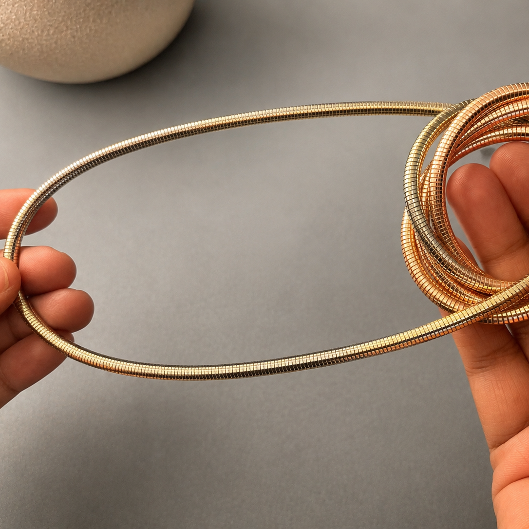 Coiled metal tube held between two hands against a gray background