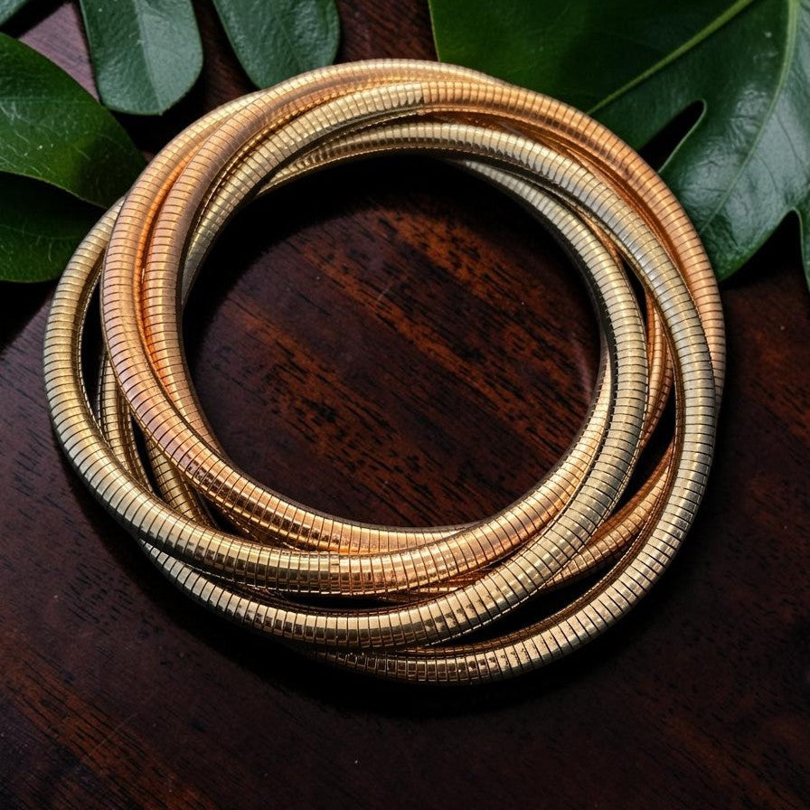 Coiled gold hose on a wooden surface with green leaves in the background