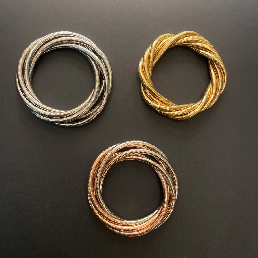 Three coiled wires in silver, gold, and bronze on a dark surface