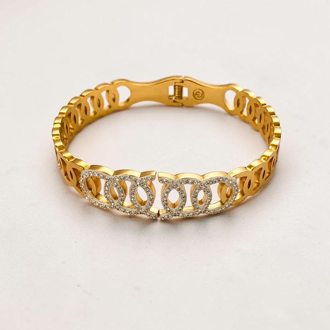 A gold-toned link bracelet with a central row of clear rhinestone-encrusted links, photographed on a plain light background.