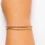 Gold tone bracelet with pink stones on a wrist against a white background