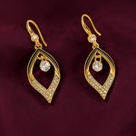 A pair of gold drop earrings with a leaf-like teardrop design, adorned with clear pavé stones and a central clear round gemstone, displayed on a dark burgundy fabric background.