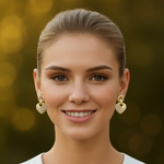 Woman wearing gold tone earrings with a blurred golden background