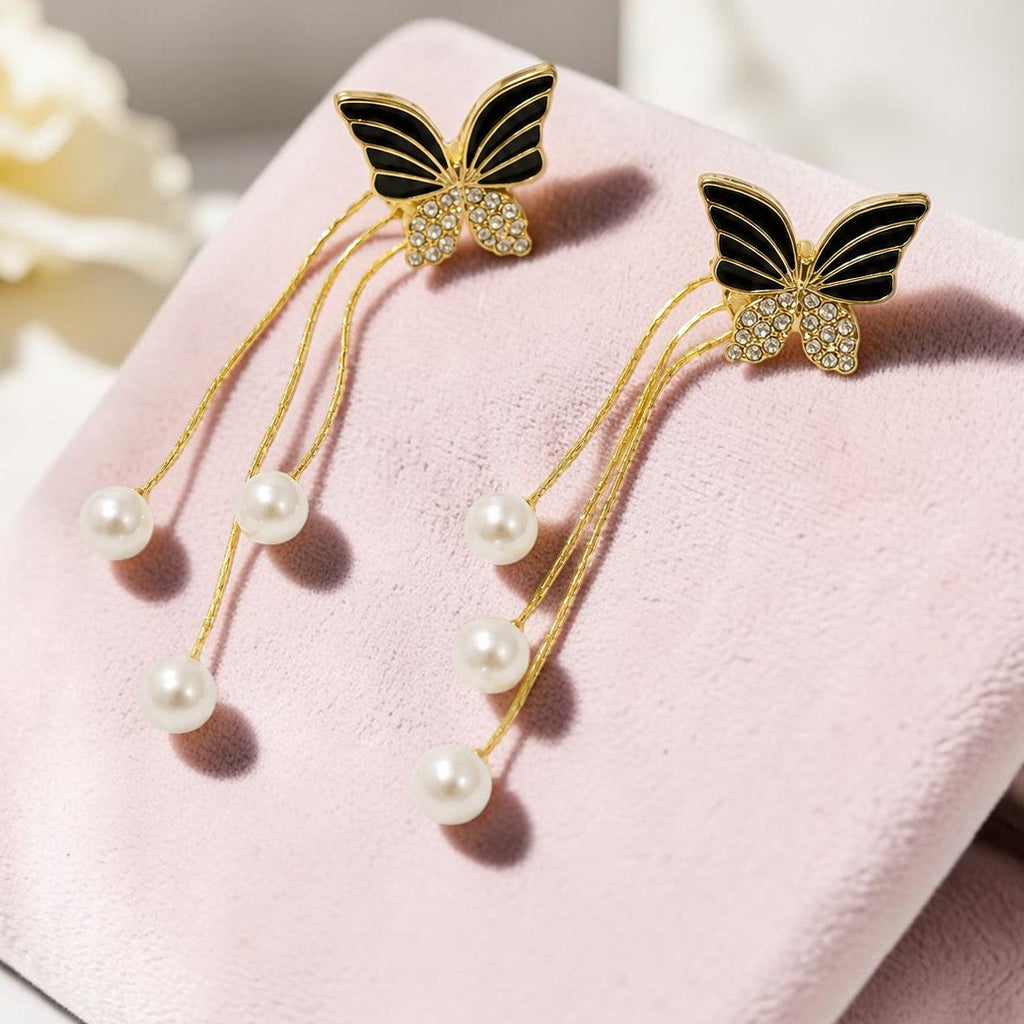 Butterfly earrings with pearl accents on a pink surface