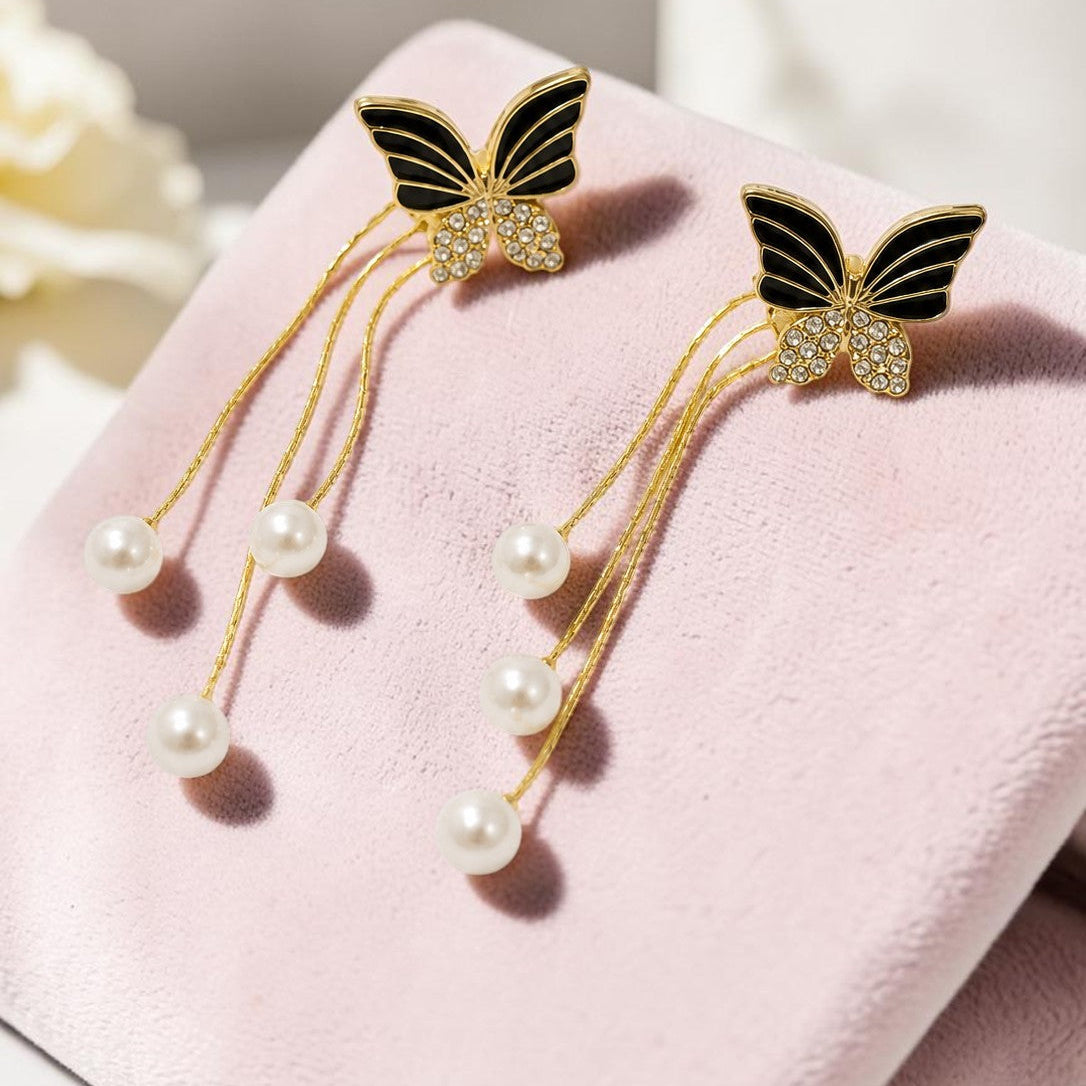 Butterfly earrings with pearl accents on a pink surface