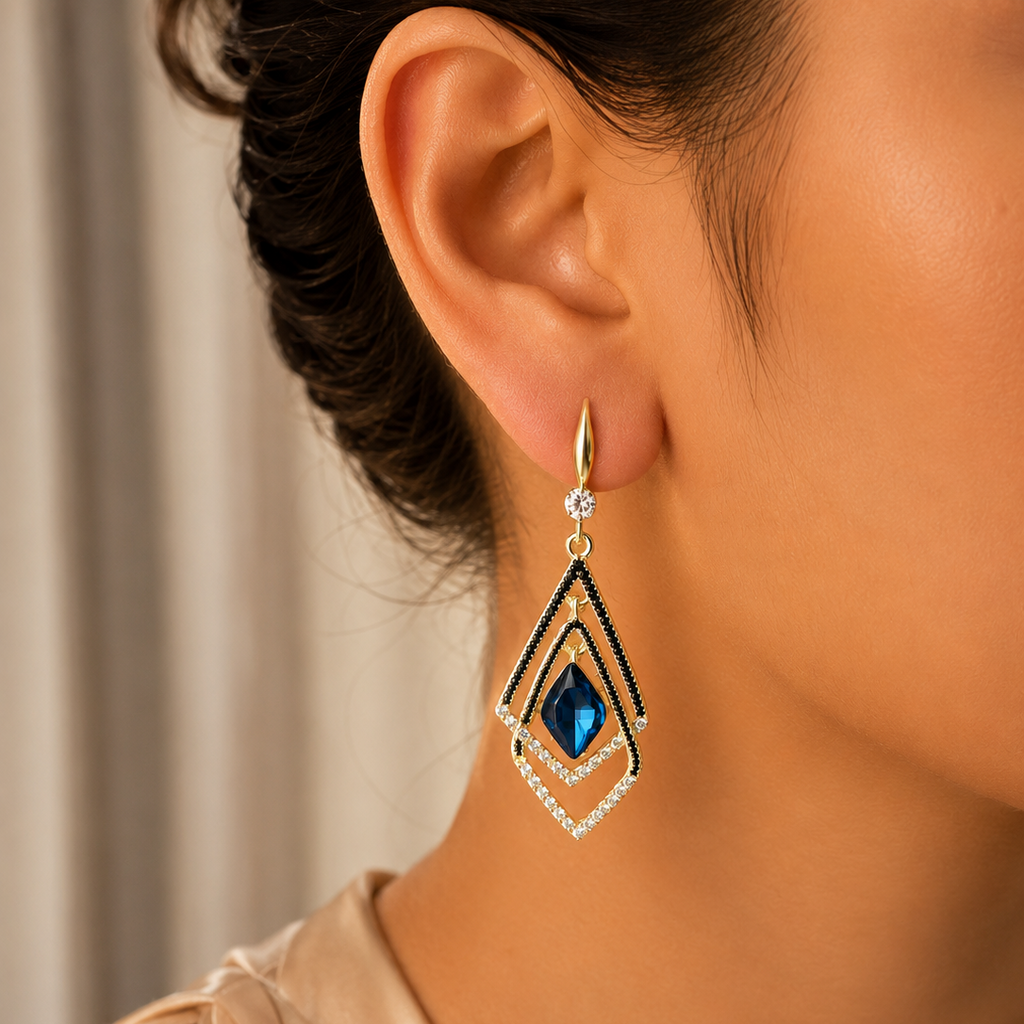 Close-up of a person wearing a diamond earring with a blue gemstone.