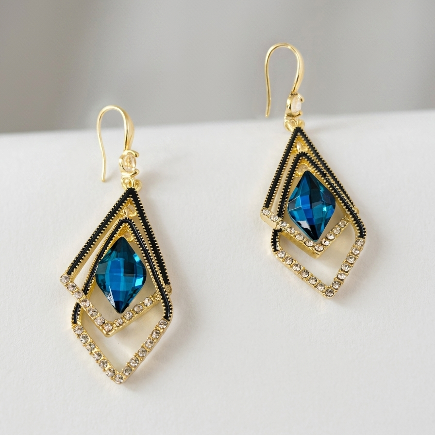 Gold tone earrings with blue gemstones on a white surface
