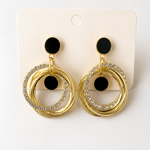 Golden hoop earrings with black pom-poms on a white card