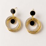 Gold hoop earrings with black centers and gemstones on a light gray background