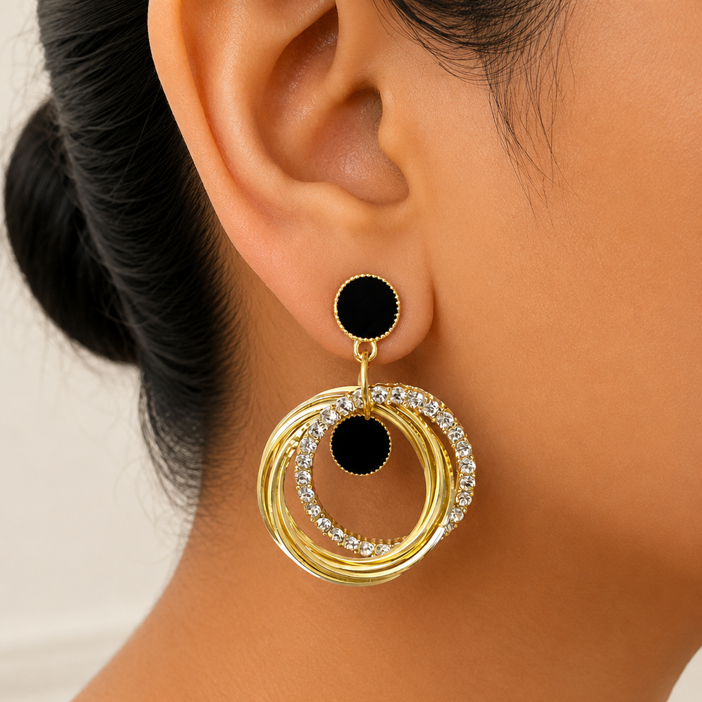 Gold and black circular earring worn by a person with a neutral background