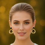 Woman wearing golden hoop earrings with black centers against a blurred background