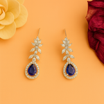 Pair of earrings with blue gemstones and american diamond-like stones on an orange background