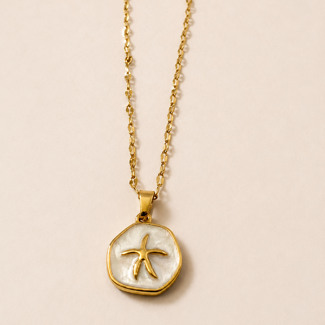 Gold tone necklace with a starfish pendant on a beige background
