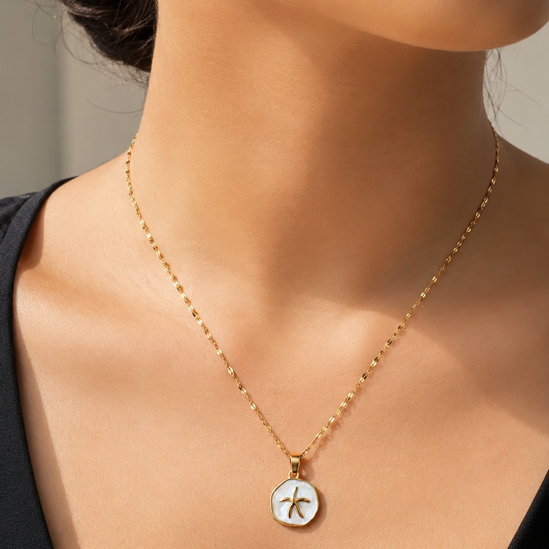 Gold tone necklace with a star pendant on a model against a neutral background