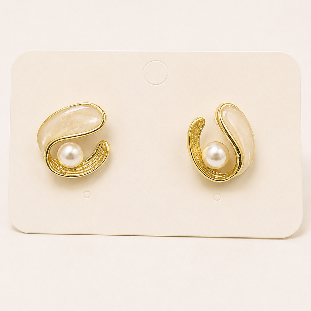 Gold tone earrings with pearl centers on a white card