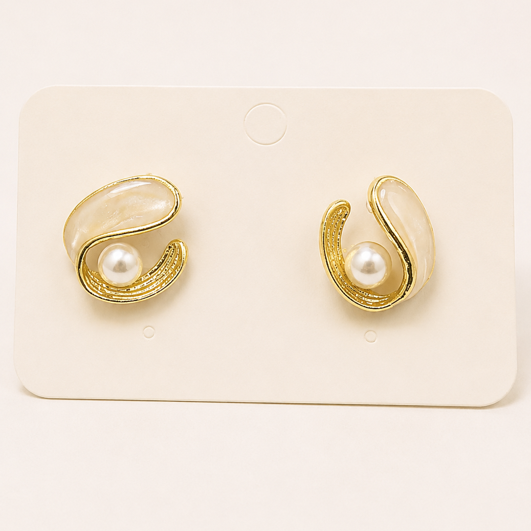 Gold tone earrings with pearl centers on a white card