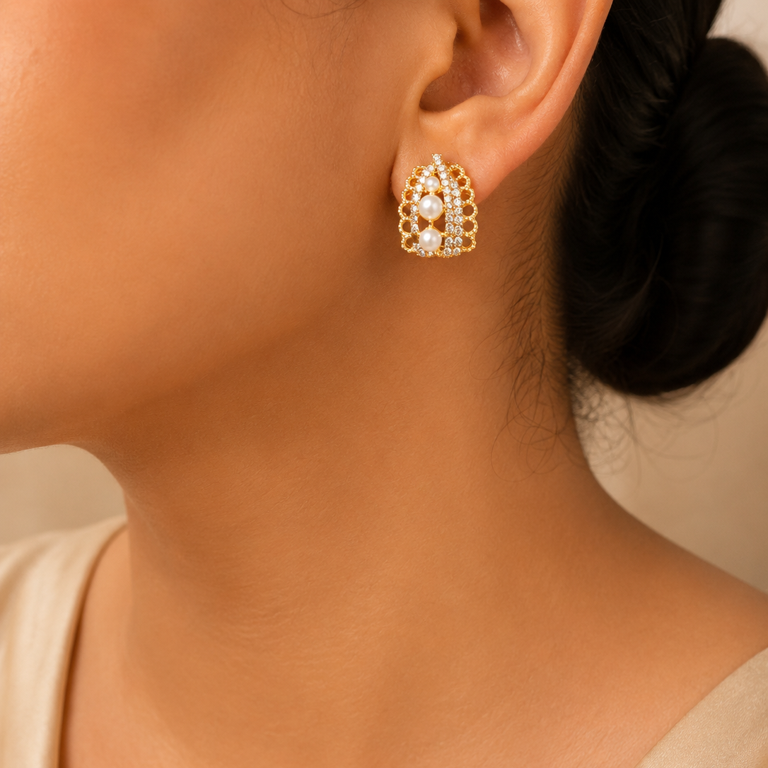 Close-up of a person wearing gold earrings with a neutral background