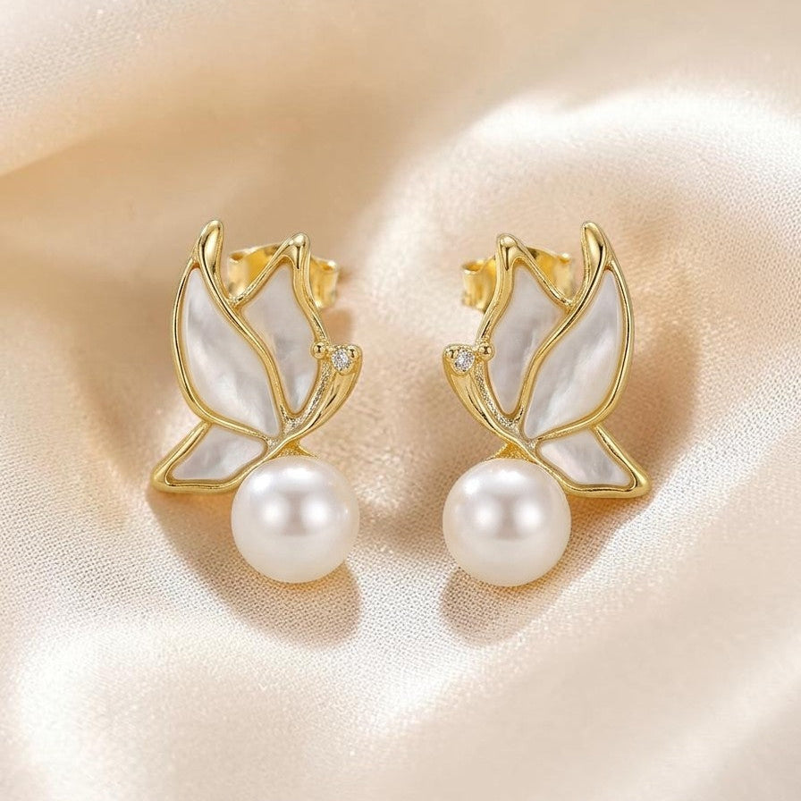 Pearl earrings with golden leaf designs on a soft beige background