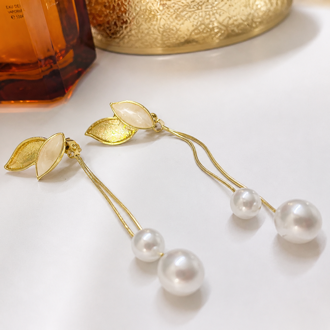 Gold tone earrings with pearls on a white surface