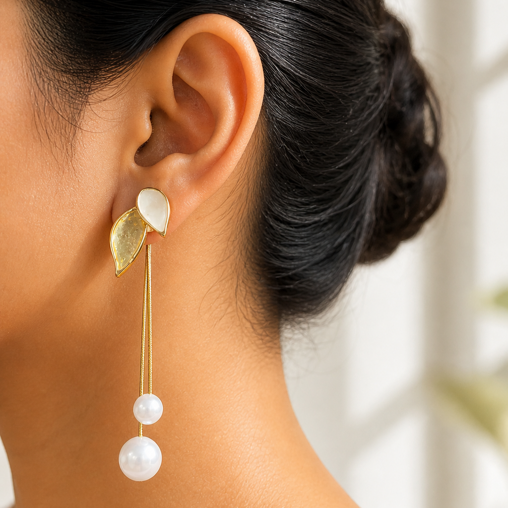 Close-up of a person wearing a gold tone and pearl earring with a blurred background