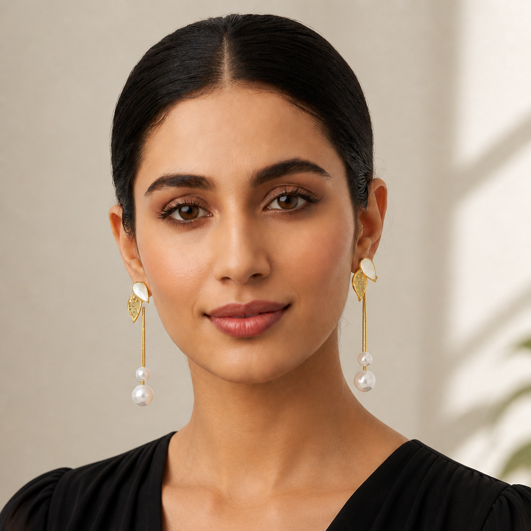 Woman wearing gold earrings with pearls against a neutral background