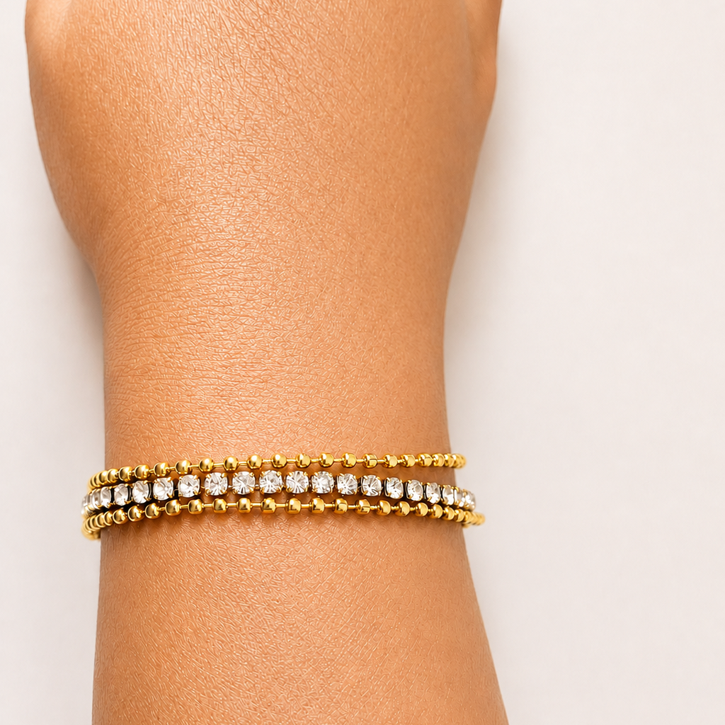 Gold tone bracelet with clear stones on a wrist against a white background