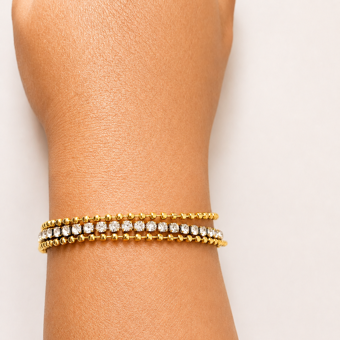 Gold tone bracelet with clear stones on a wrist against a white background