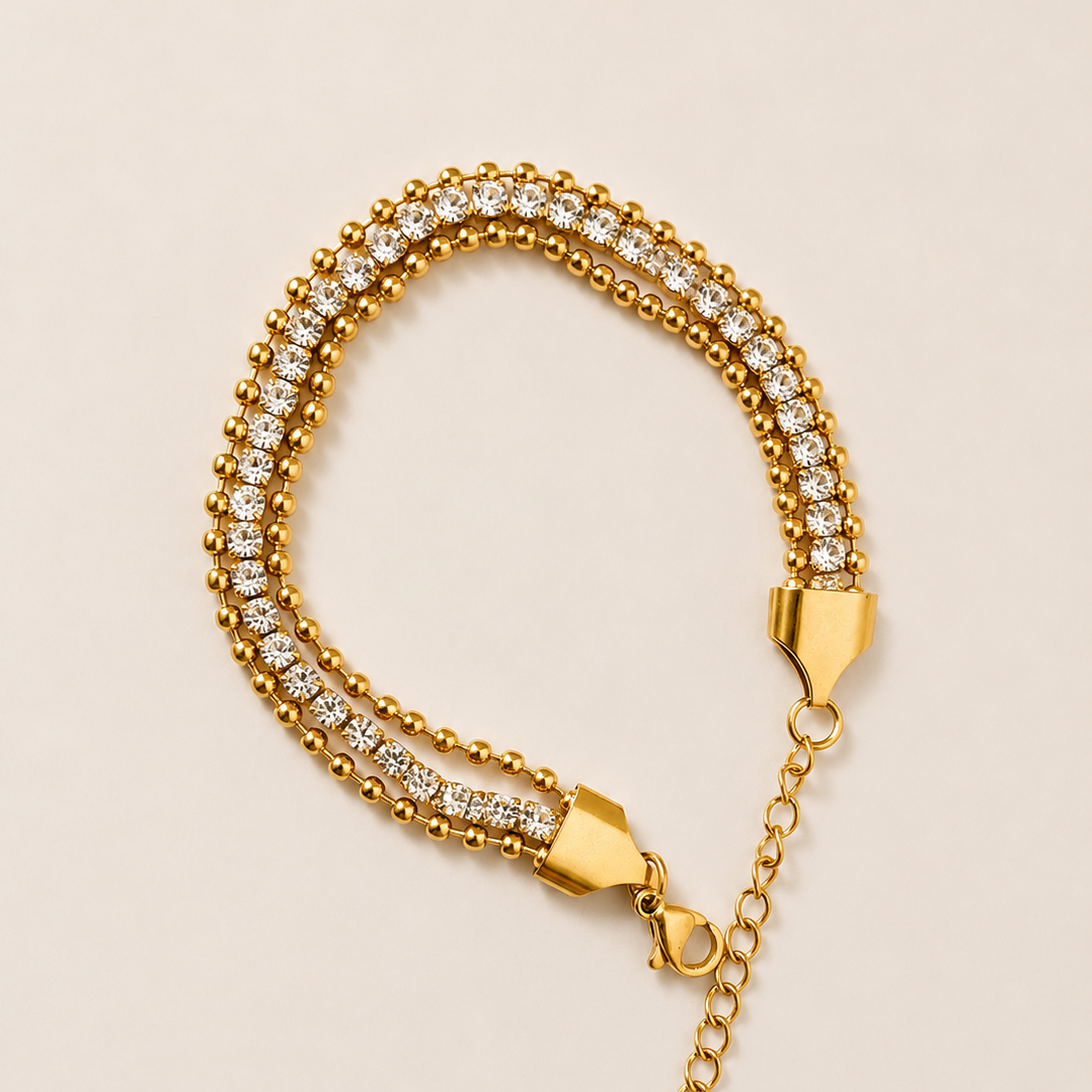 Gold tone bracelet with diamond accents on a beige background
