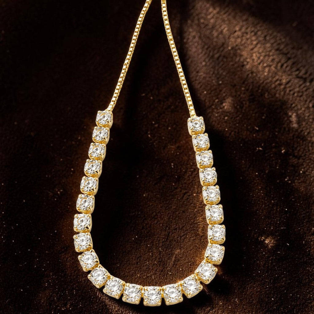Gold tone and crystal teardrop-shaped necklace on a dark background