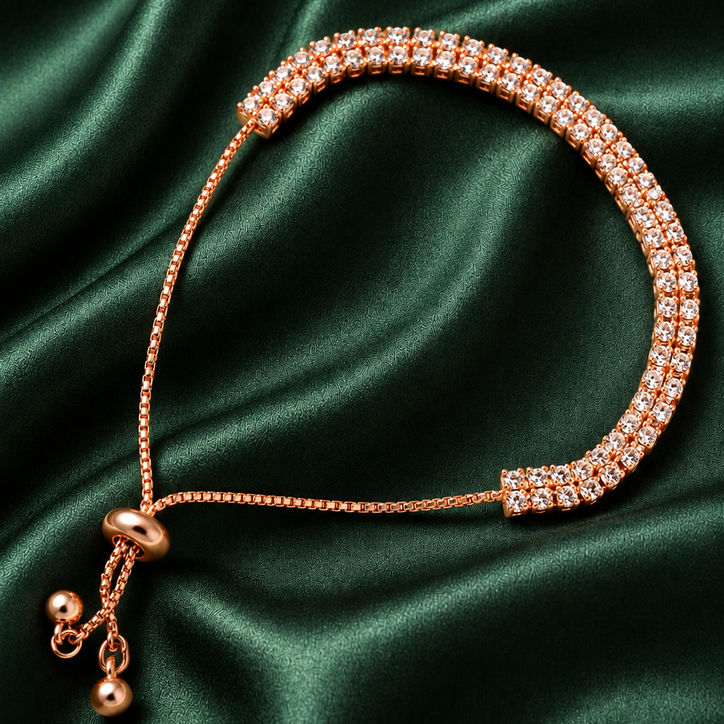 A rose gold adjustable chain bracelet with two rows of clear pavé stones, displayed on a draped dark green satin fabric background.