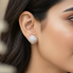 Close-up of a woman wearing a silver earring with a textured design.