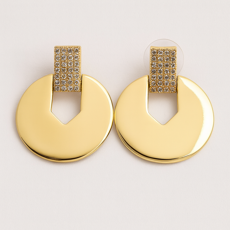 Gold tone earrings with circular designs on a light gray background