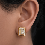 Gold tone earring with a clear gemstone worn by a person