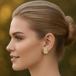 Woman with styled hair and gold tone earrings against a blurred background