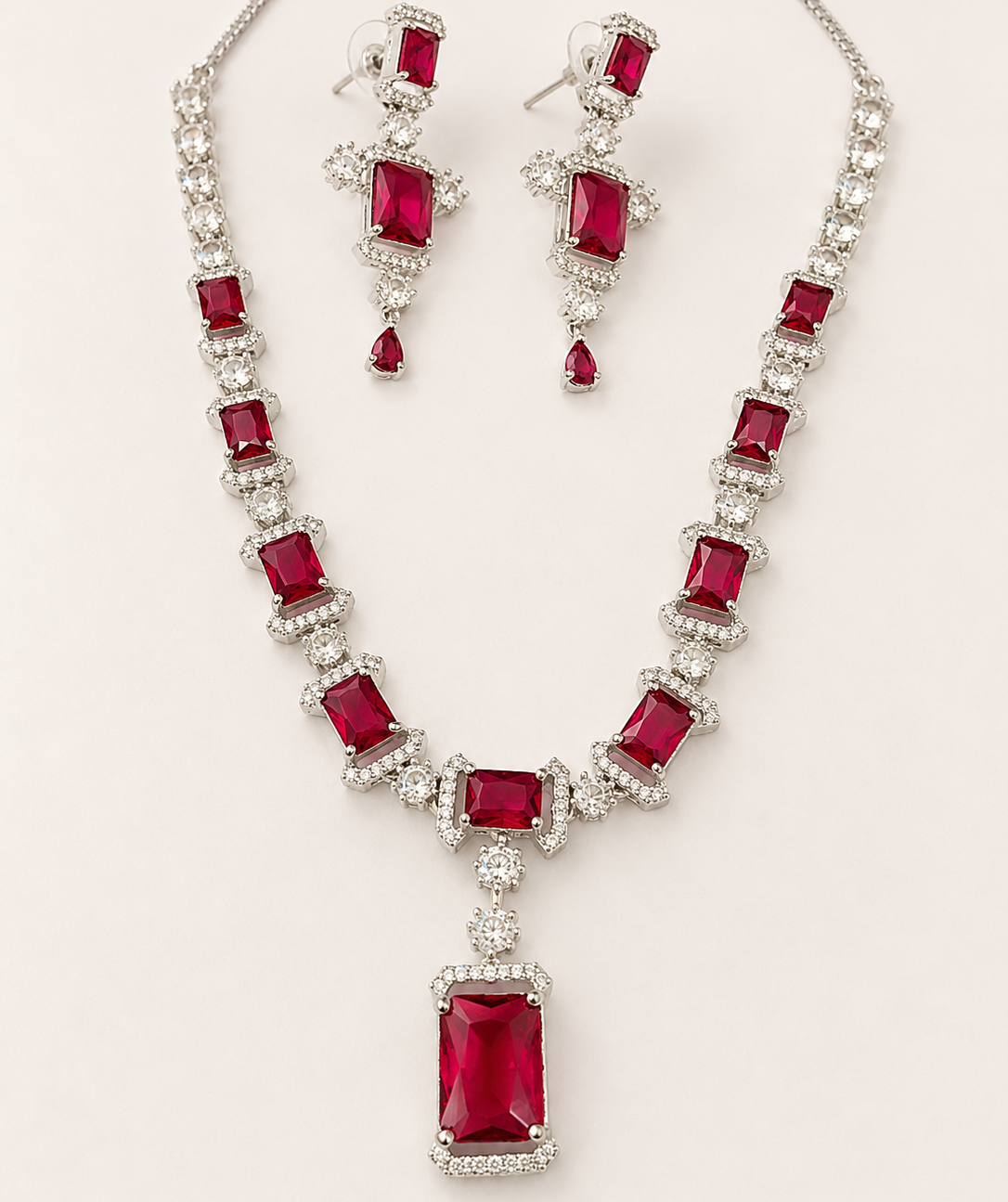 Jewelry set with necklace and earrings featuring red gemstones on a white background