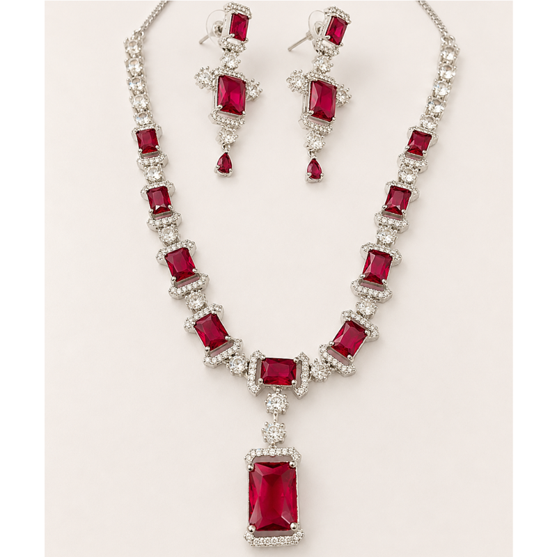 Jewelry set with necklace and earrings featuring red gemstones on a white background