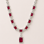 Necklace with red gemstones and clear stones on a light pink background