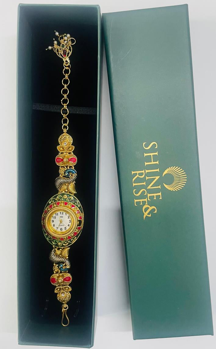 A gold-plated ornate watch bracelet with colorful enamel details, displayed inside an open black presentation box next to its green branded box lid. The brand 'SHINE RISE' is printed in gold on the green lid.