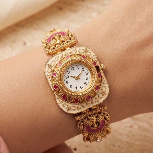 A close-up of a gold-toned ornate watch with pink enamel details and a white dial, worn on a person's wrist against a warm beige background.