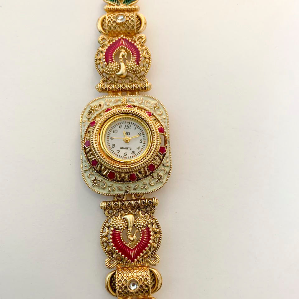 A gold-plated traditional Indian watch with intricate enameled details in red, green, and gold, featuring peacock and swan motifs on a white background.